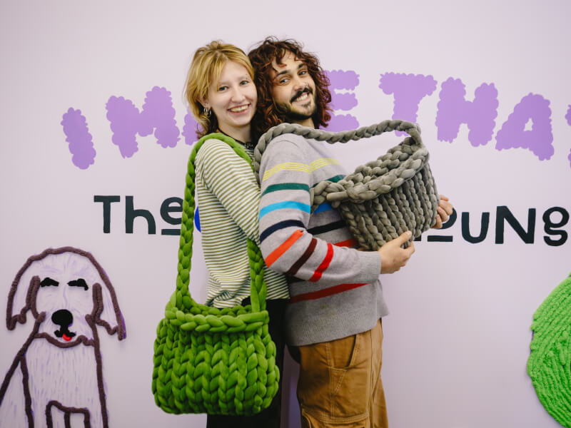 A couple posing with the crochet bags they've made